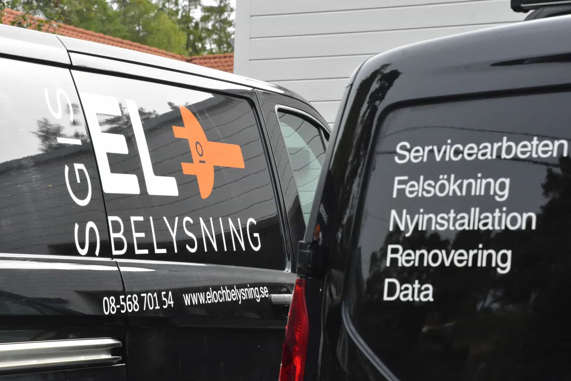 Två svarta servicebilar. En med "GIS EL O BELYSNING" och skiftnyckellogga. Den andra listar tjänster som Servicearbeten