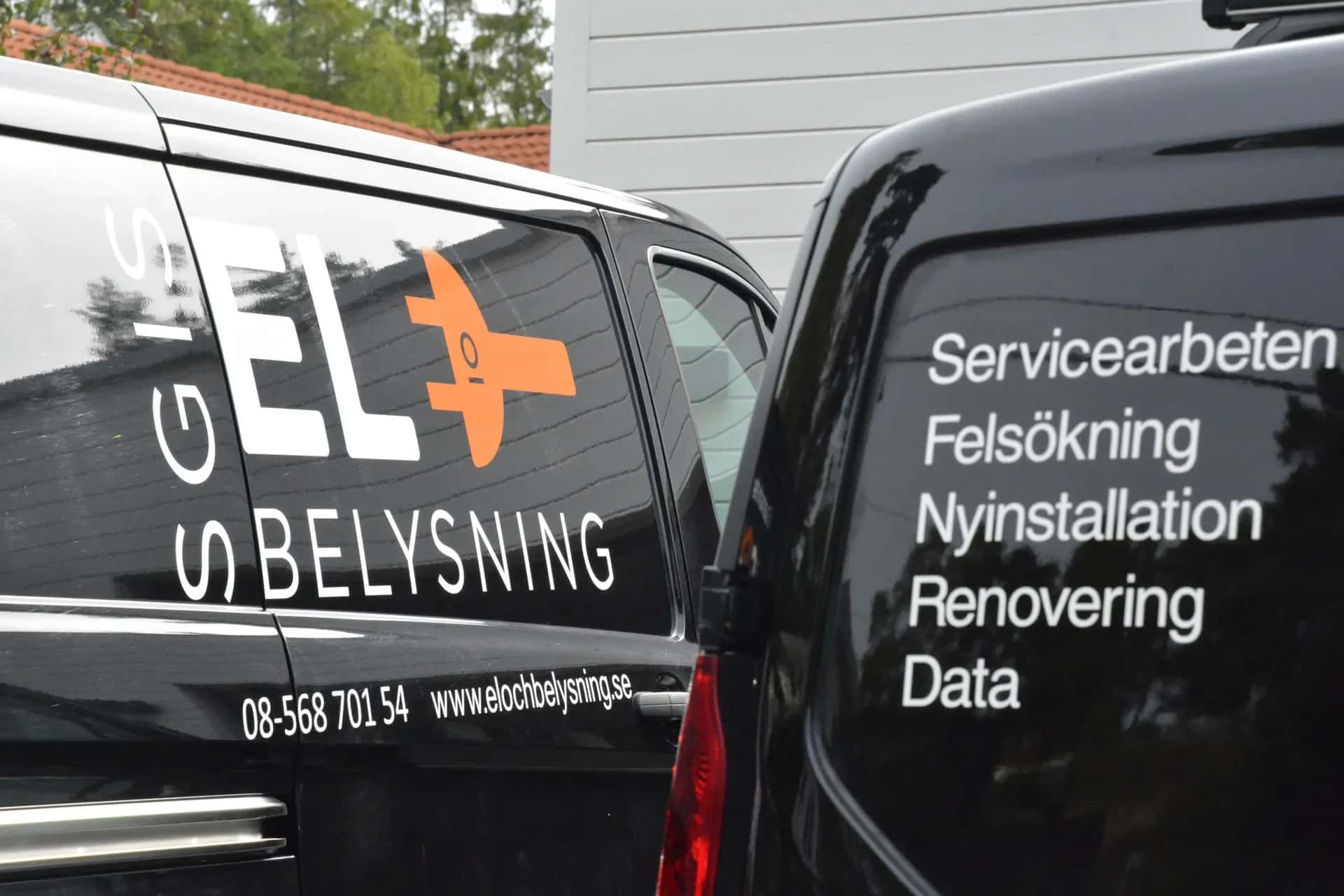 Två svarta servicebilar. En med "GIS EL O BELYSNING" och skiftnyckellogga. Den andra listar tjänster som Servicearbeten