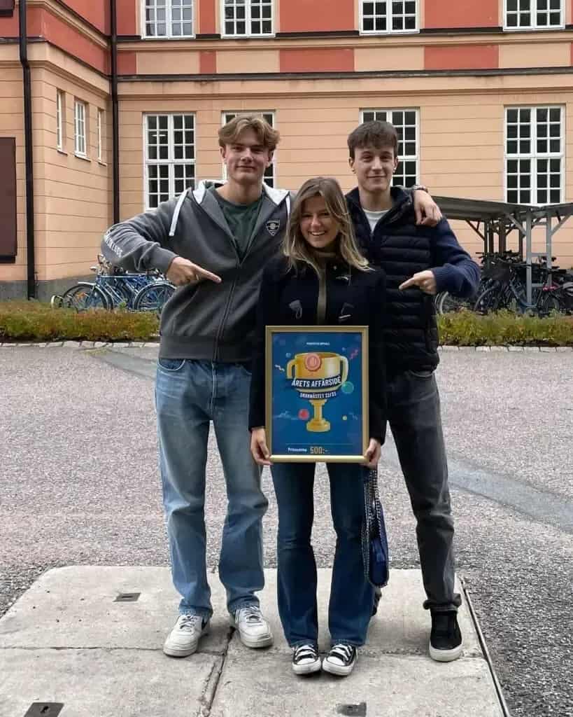 Tre personer med skylt "Årets Affärssida". Hus och cyklar i bakgrunden